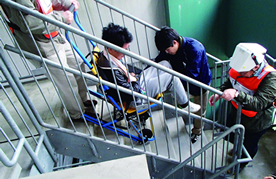 ▲非常階段で要援護者の避難訓練を支援する東北福祉大学Team Bousaisiの皆さん
